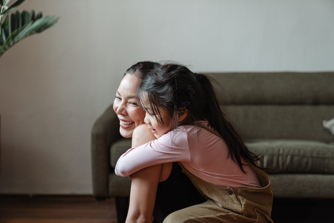 services-01 Smiling mother and daughter sharing a warm embrace in a cozy home setting.